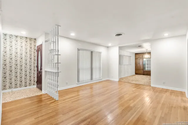 a view of an empty room with wooden floor and a bathroom