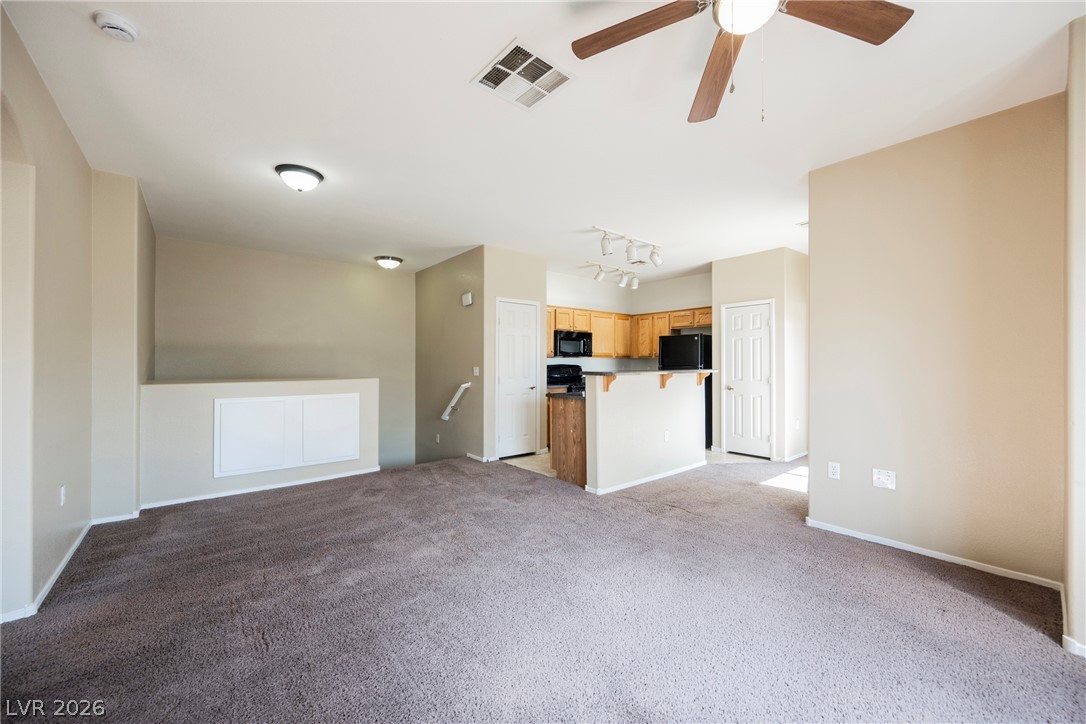 6320 Snap Ridge Street, Unit 201 North Las Vegas, NV 89081 - Photo 19 of 56 An open-concept living area seamlessly connects to a compact kitchen with wood cabinetry.