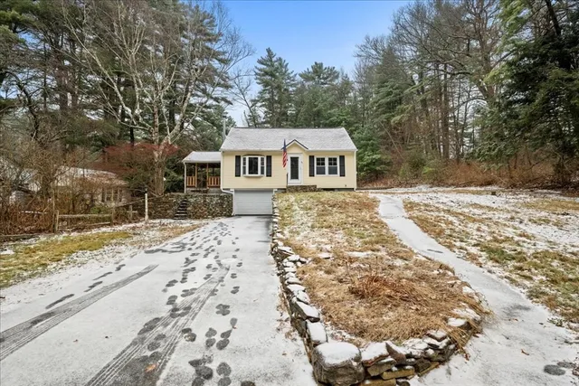 a front view of a house with a yard covered with snow and trees