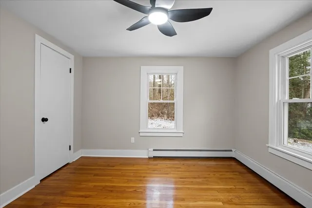 a view of an empty room with window and wooden floor