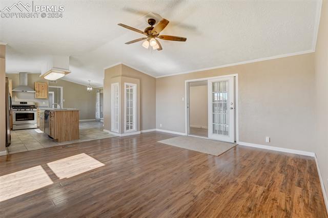 6240 Night Train Lane Yoder, CO 80864 - Photo 10 of 50 Unfurnished living room featuring ceiling fan, light tile flooring, ornamental molding, lofted ceiling, and sink