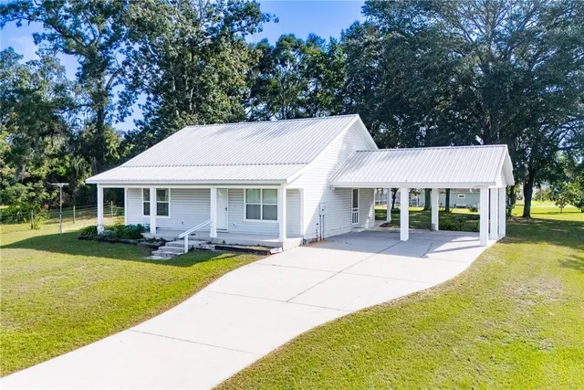 a front view of a house with garden and trees