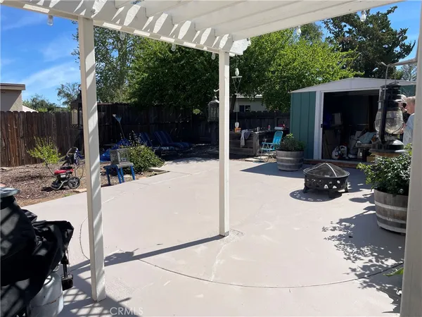 a view of a patio with table and chairs potted plants and floor to ceiling window and wooden fence
