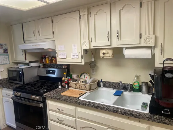 a kitchen with granite countertop a sink stove and cabinets