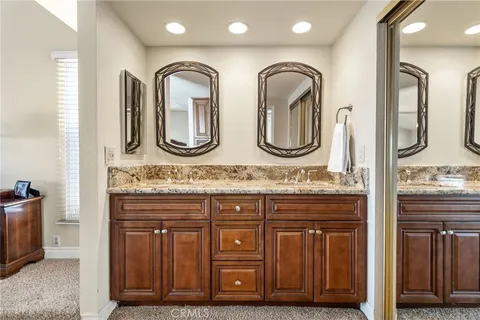a bathroom with a granite countertop double vanity sink a mirror and a toilet