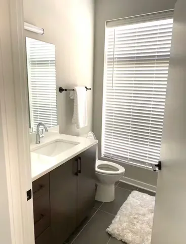a bathroom with a sink toilet a mirror and next to a window