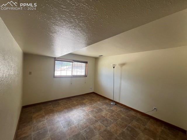 7280 Mathews Road Colorado Springs, CO 80908 - Photo 26 of 31 Additional living space featuring a textured ceiling and tile patterned flooring