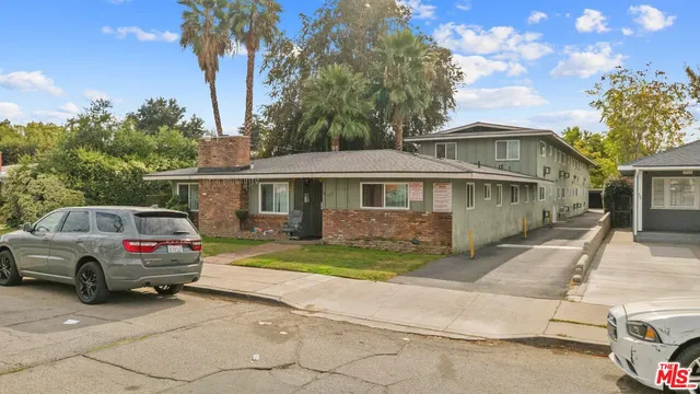 a front view of a house with a garden and trees