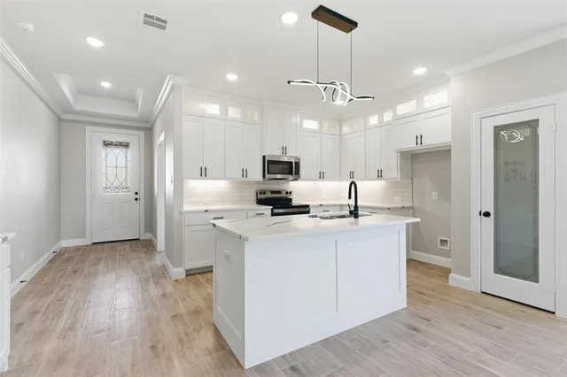 a large kitchen with stainless steel appliances kitchen island a large counter space and wooden floor