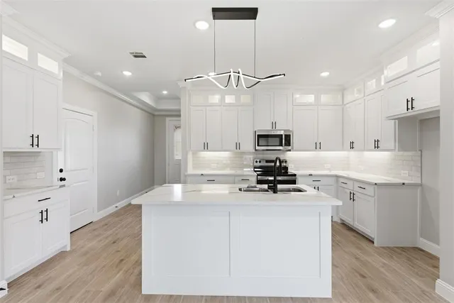 a kitchen with kitchen island a sink stainless steel appliances and white cabinets