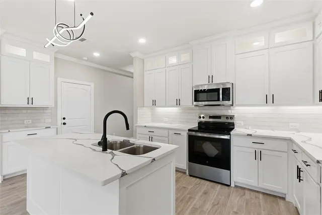 a kitchen with stainless steel appliances granite countertop a sink a stove top oven a counter space and cabinets