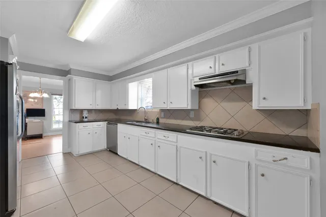 a large white kitchen with granite countertop white cabinets