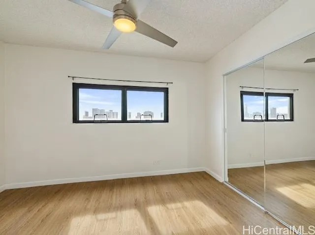 a view of empty room with wooden floor and fan