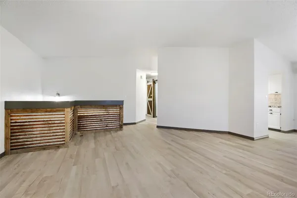 a view of an empty room with wooden floor and windows