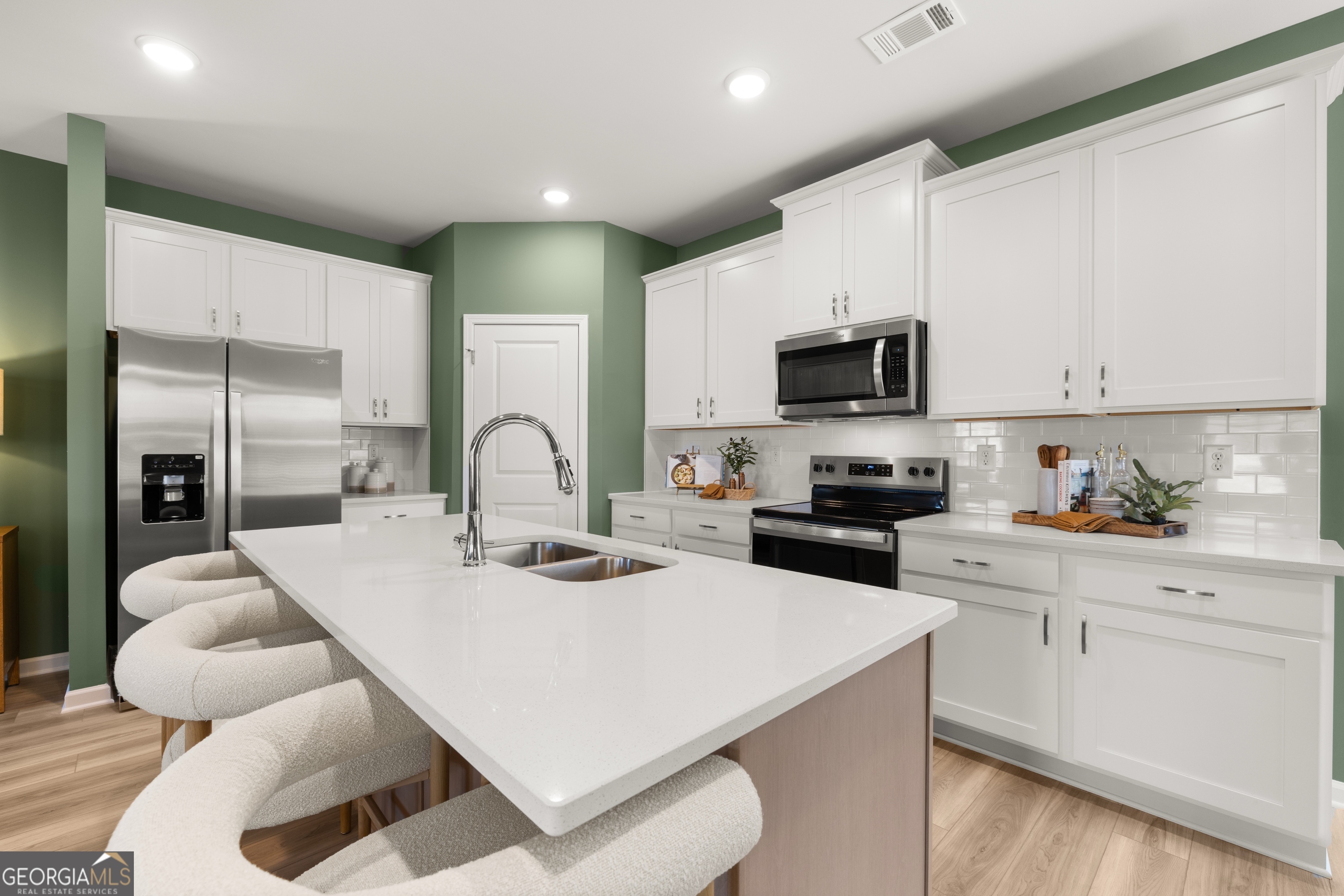 3263 Lake Carlton Road, Unit 23 Loganville, GA 30052 - Photo 6 of 33 a kitchen with a sink a stove and white cabinets