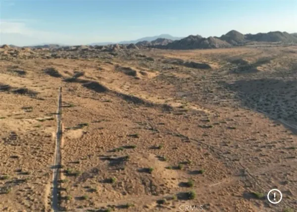 a view of a dry yard with mountains and green space