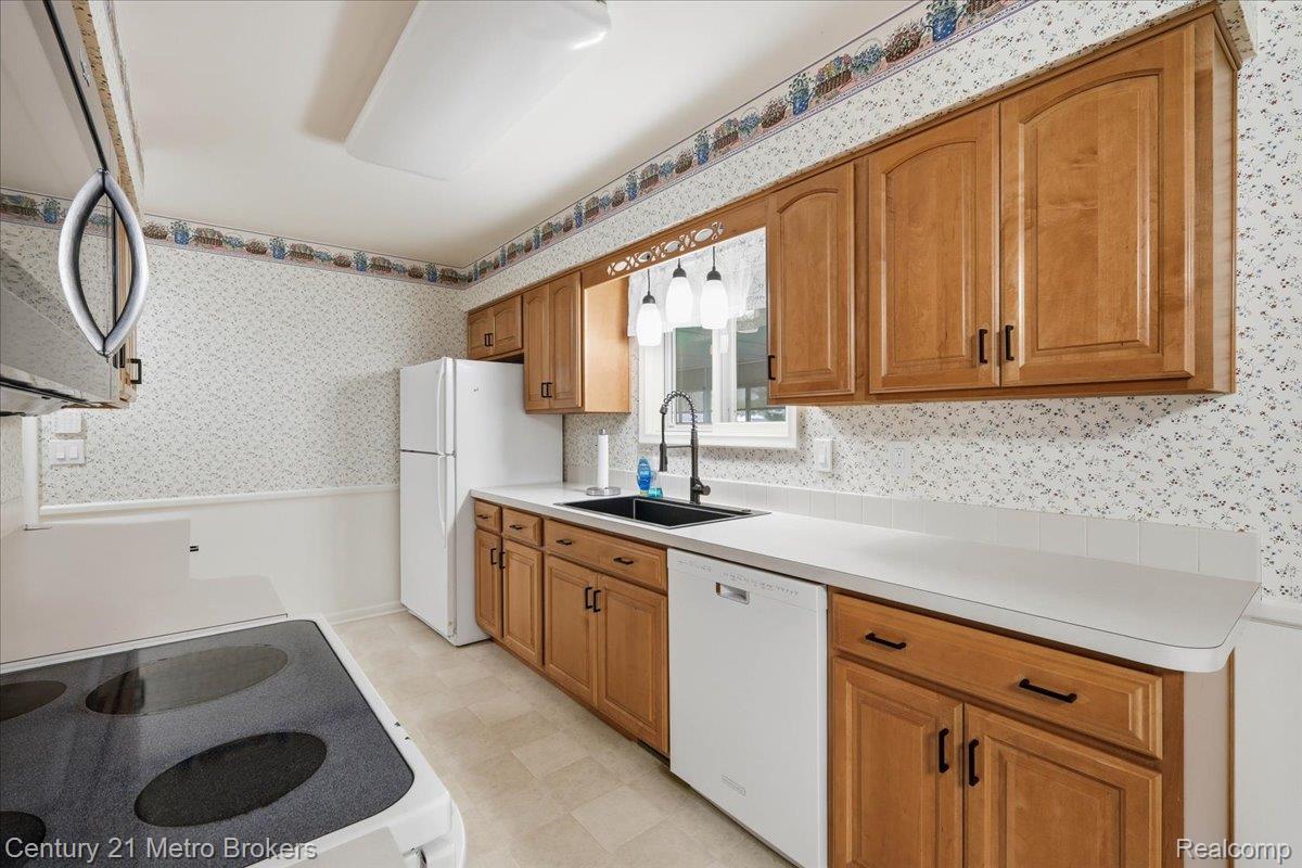 5457 North Seymour Road Flushing, MI 48433 - Photo 19 of 43 Kitchen with wallpapered walls, light floors, wood finish cabinetry, white appliances, and light countertops