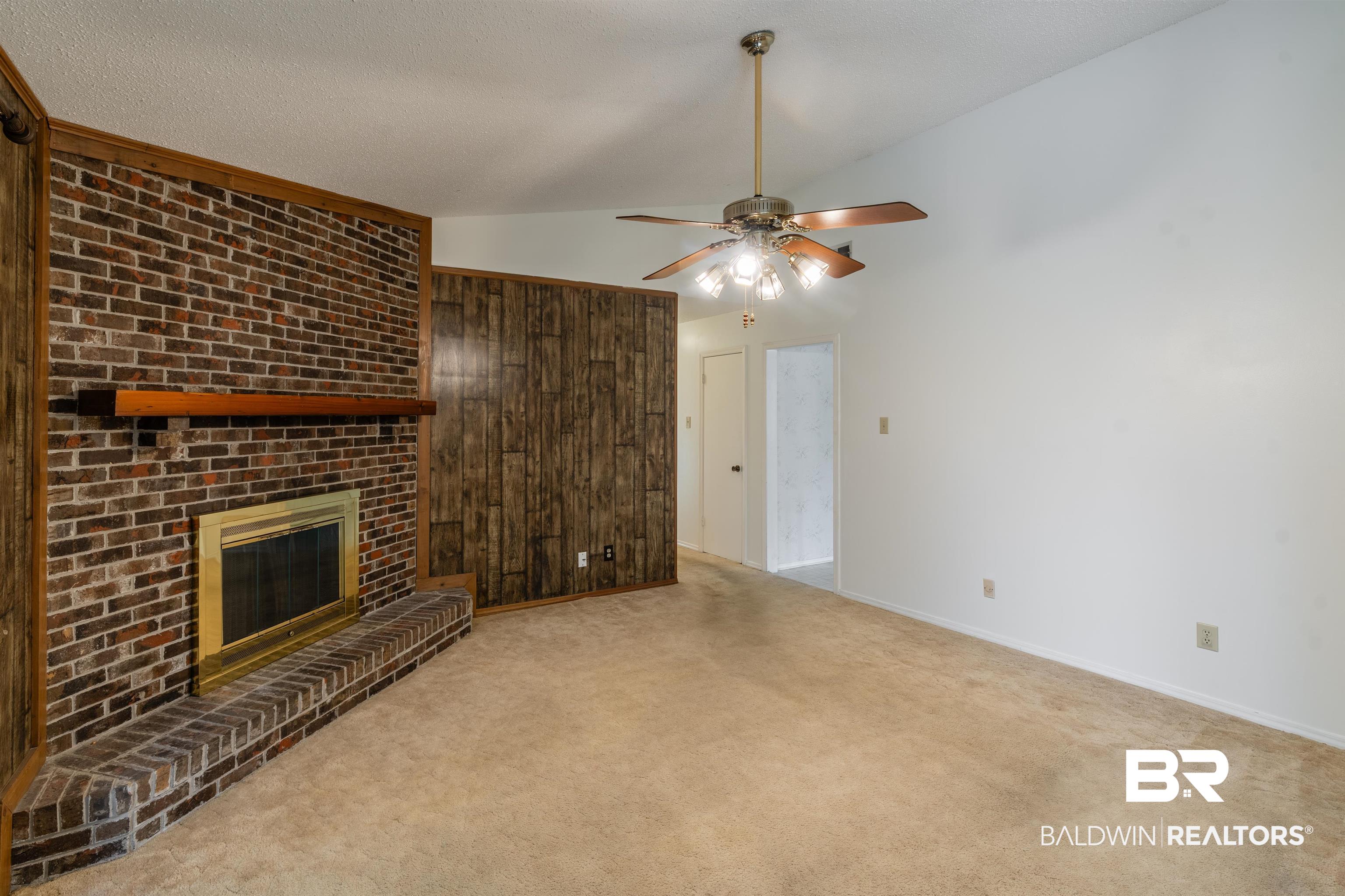 9751 Pine Knoll Road Mobile, AL 36608 - Photo 11 of 36 Unfurnished living room featuring a fireplace, ceiling fan, carpet floors, a textured ceiling, and wooden walls