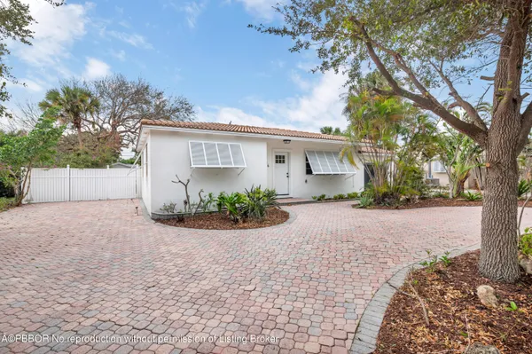 front view of house with a yard and trees
