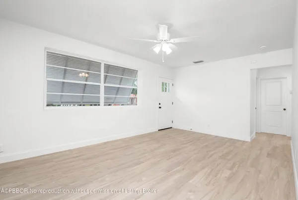 an empty room with wooden floor closet and windows