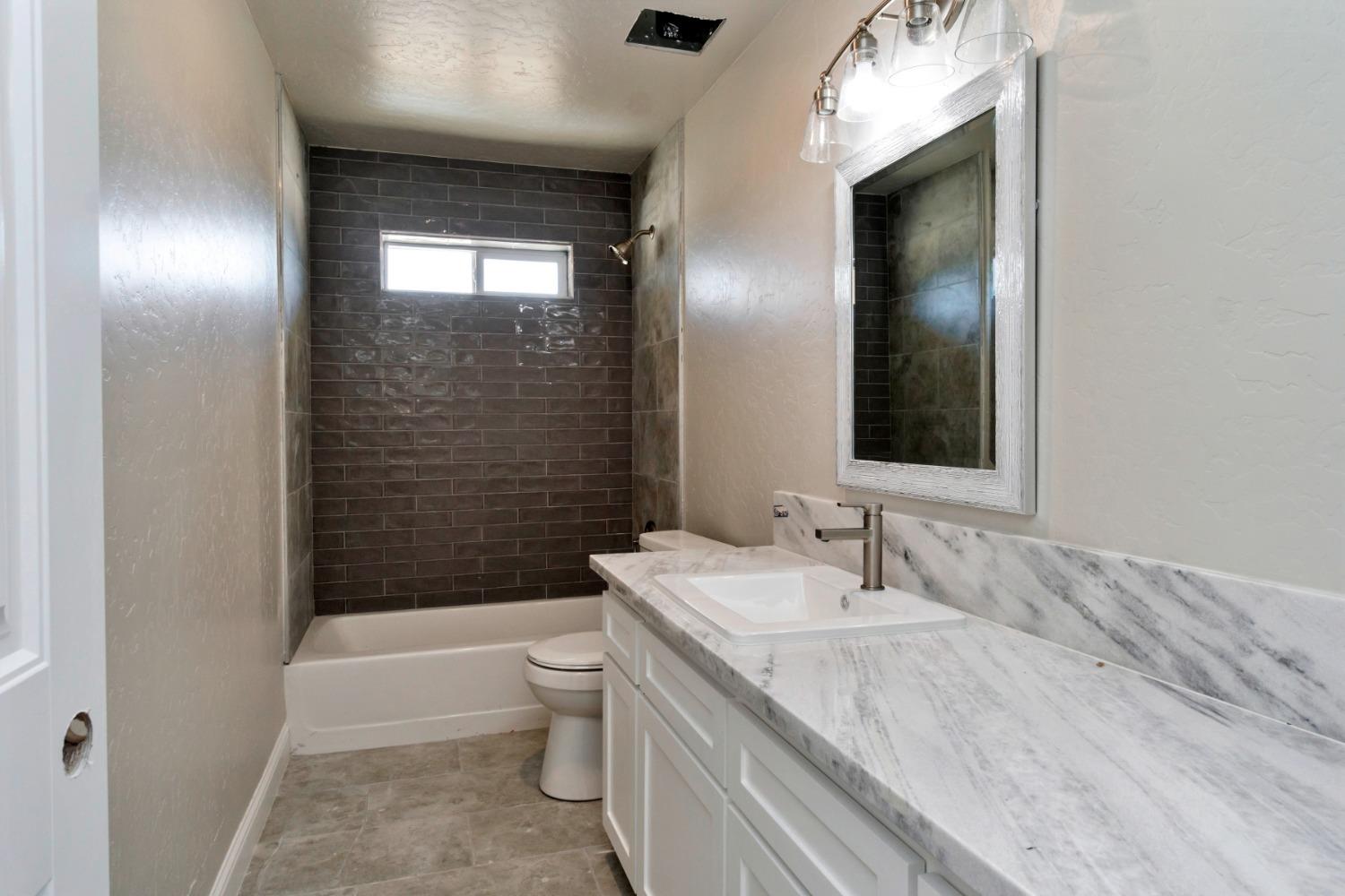21250 Steward Road Madera, CA 93638 - Photo 17 of 40 a bathroom with a granite countertop sink toilet and shower