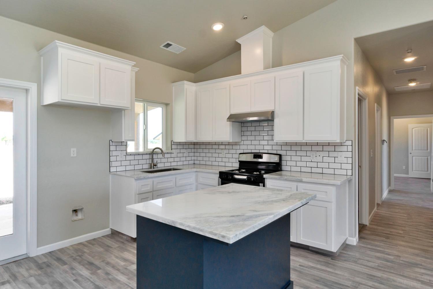 21250 Steward Road Madera, CA 93638 - Photo 27 of 40 a kitchen with a sink a stove a refrigerator and white cabinets