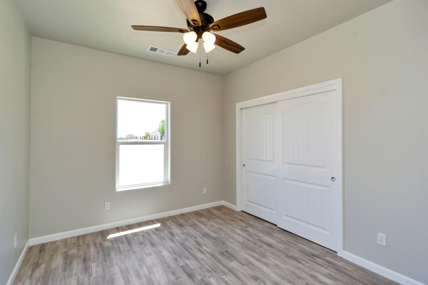 21250 Steward Road Madera, CA 93638 - Photo 31 of 40 an empty room with wooden floor ceiling fan and windows