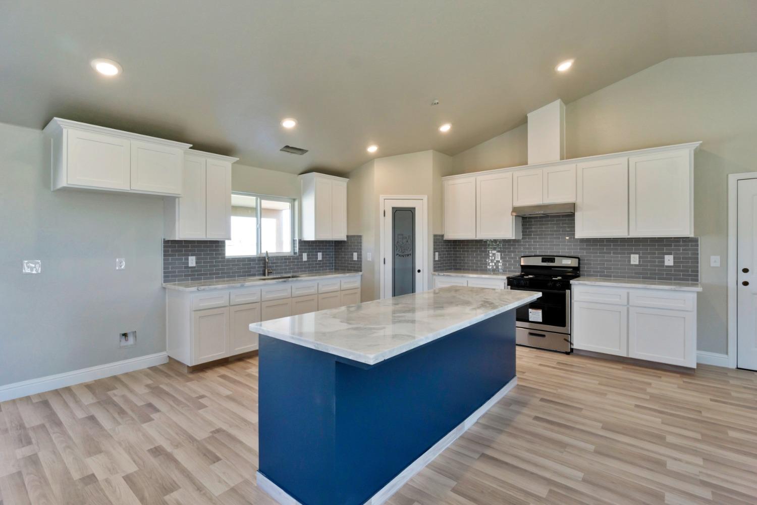 21250 Steward Road Madera, CA 93638 - Photo 8 of 40 a large kitchen with stainless steel appliances granite countertop a stove a sink dishwasher and a refrigerator with wooden floor