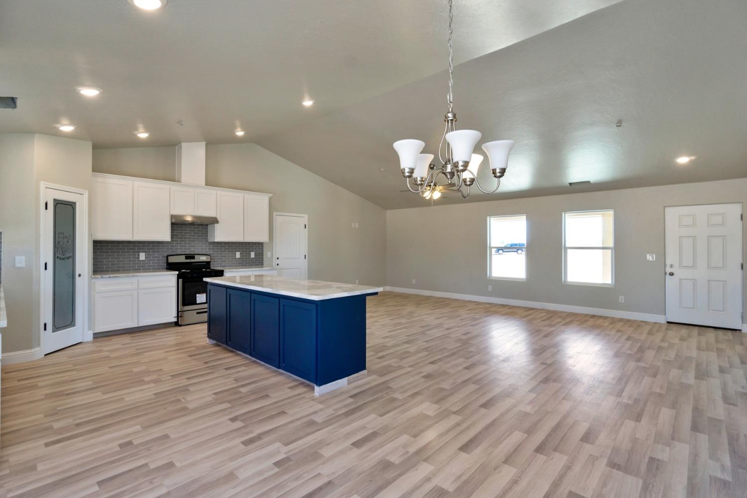 21250 Steward Road Madera, CA 93638 - Photo 9 of 40 a large kitchen with kitchen island a sink dishwasher a refrigerator and a stove with wooden floor