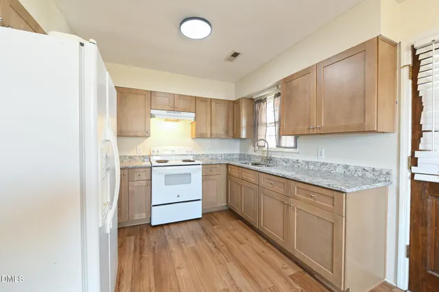 a kitchen with granite countertop white cabinets and white appliances