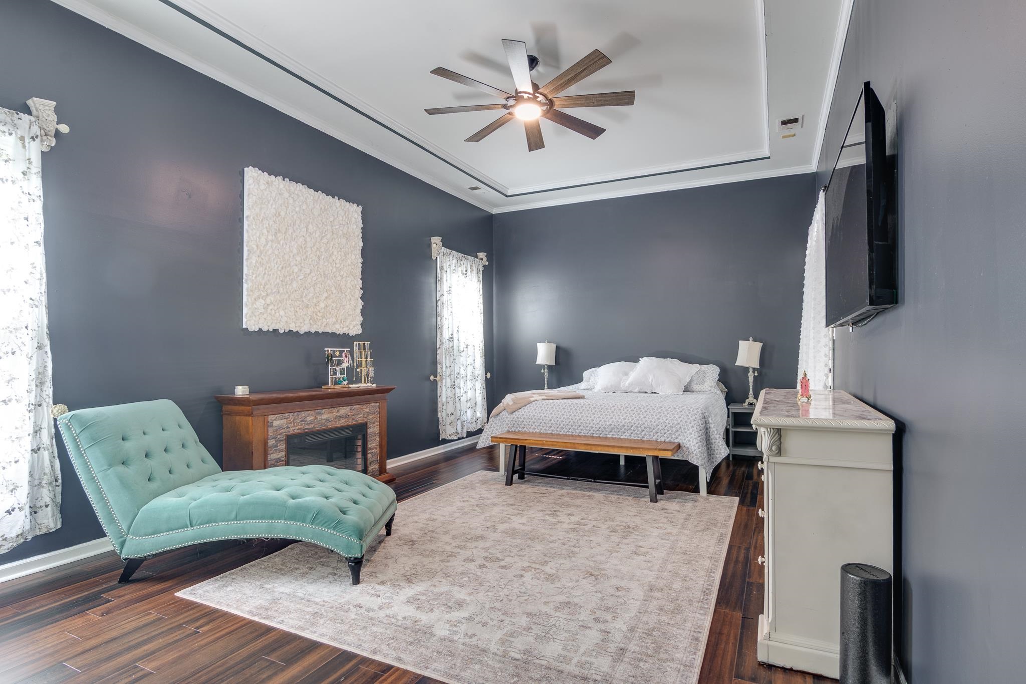 779 Early Earner Cove Collierville, TN 38017 - Photo 13 of 29 Recessed tray ceiling with crown molding, dark wood-finish flooring, and a stone-clad fireplace with a wood mantle