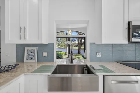 a kitchen that has a sink and a stove with white countertops