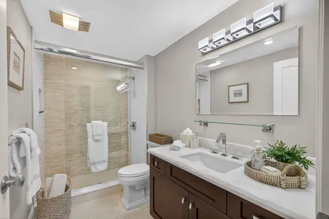 a bathroom with a granite countertop sink toilet a large mirror and shower