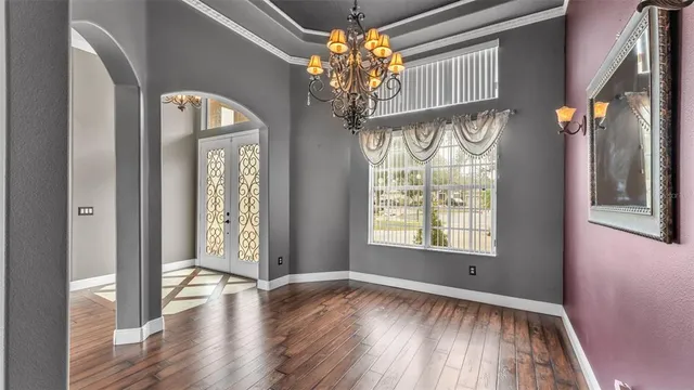 a view of an empty room and window and chandelier fan