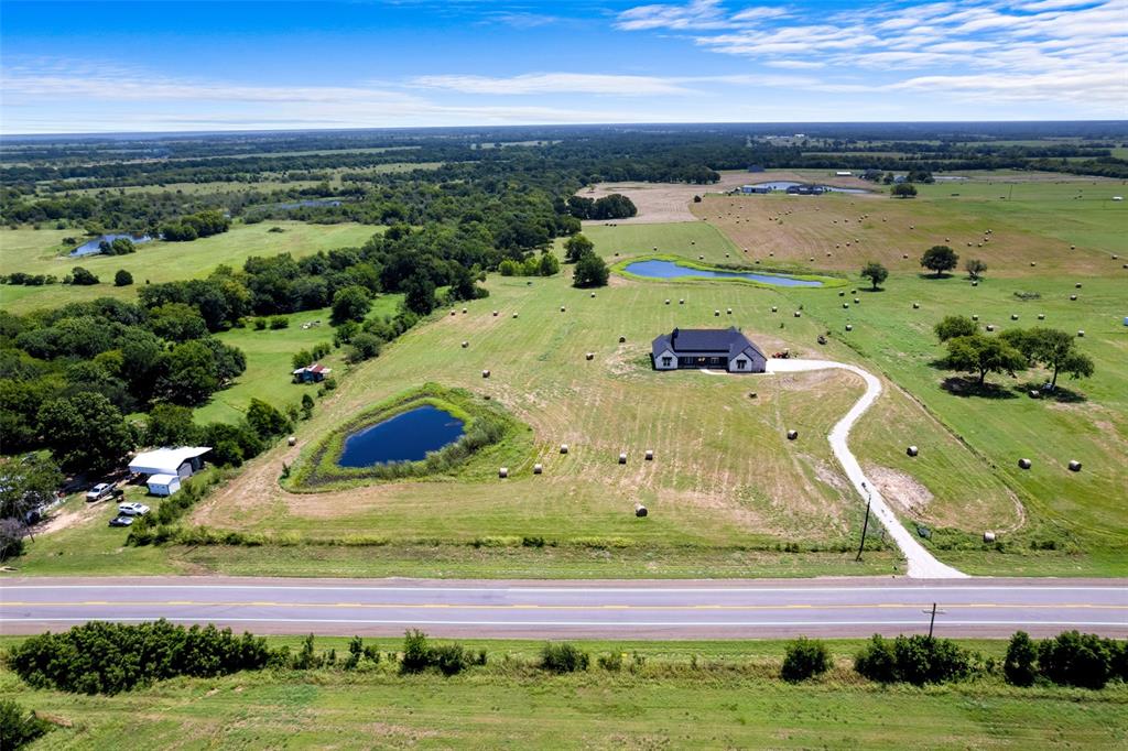 4411 Fm 751 Wills Point Wills Point, TX 75169 - Photo 37 of 40 Expansive rural property featuring a modern single-story residence with a dark roof, a private pond, mature trees, and a winding driveway
