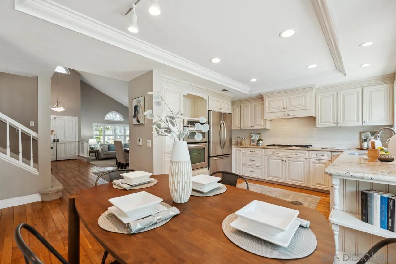 7914 Corte Cardo Carlsbad, CA 92009 - Photo 16 of 61 a kitchen with stainless steel appliances wooden floor dining table and chairs