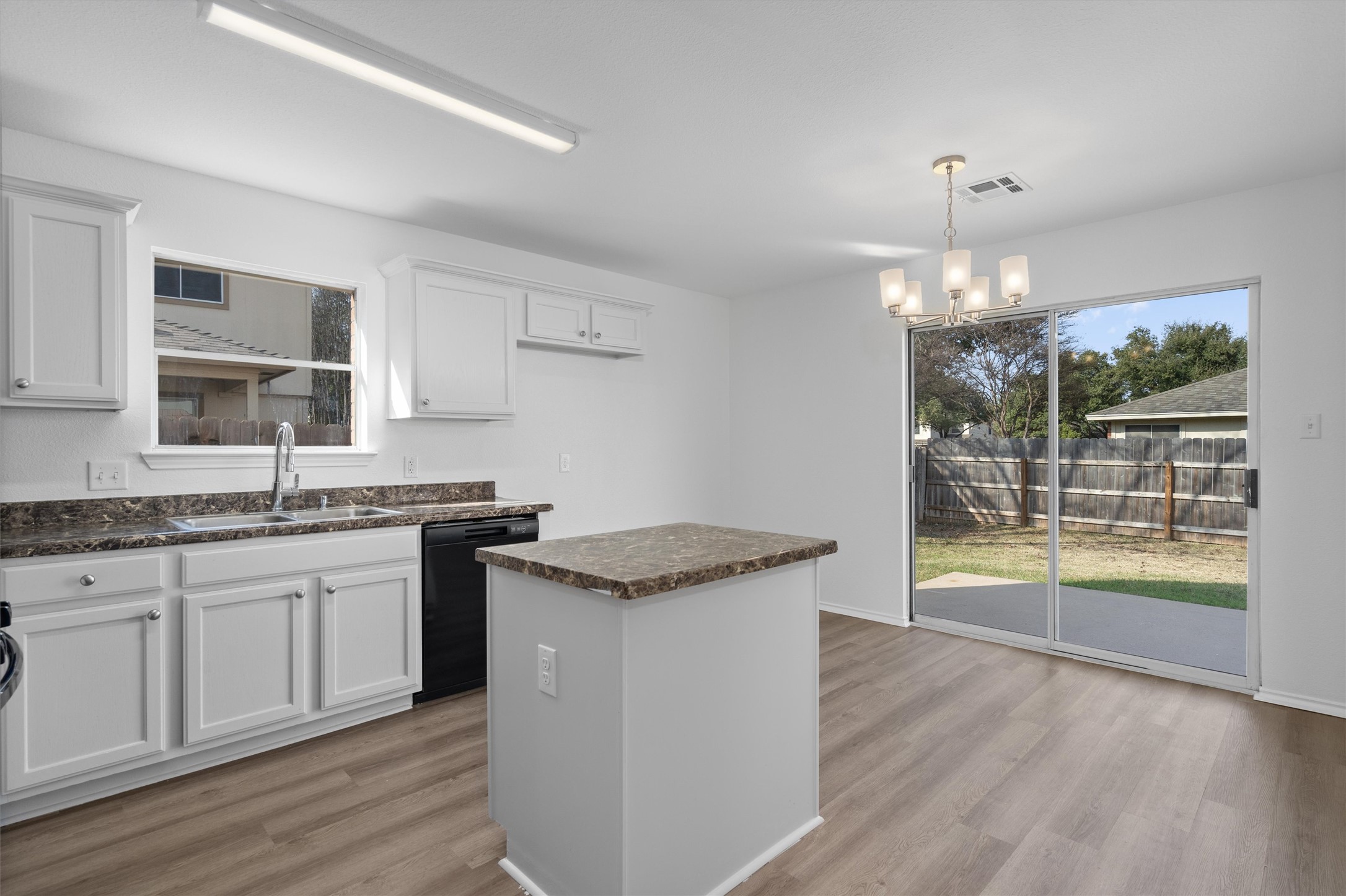 2101 Jester Farms Road Round Rock, TX 78664 - Photo 7 of 24 Kitchen featuring light wood-type flooring, black dishwasher, a kitchen island, hanging light fixtures, and white cabinets