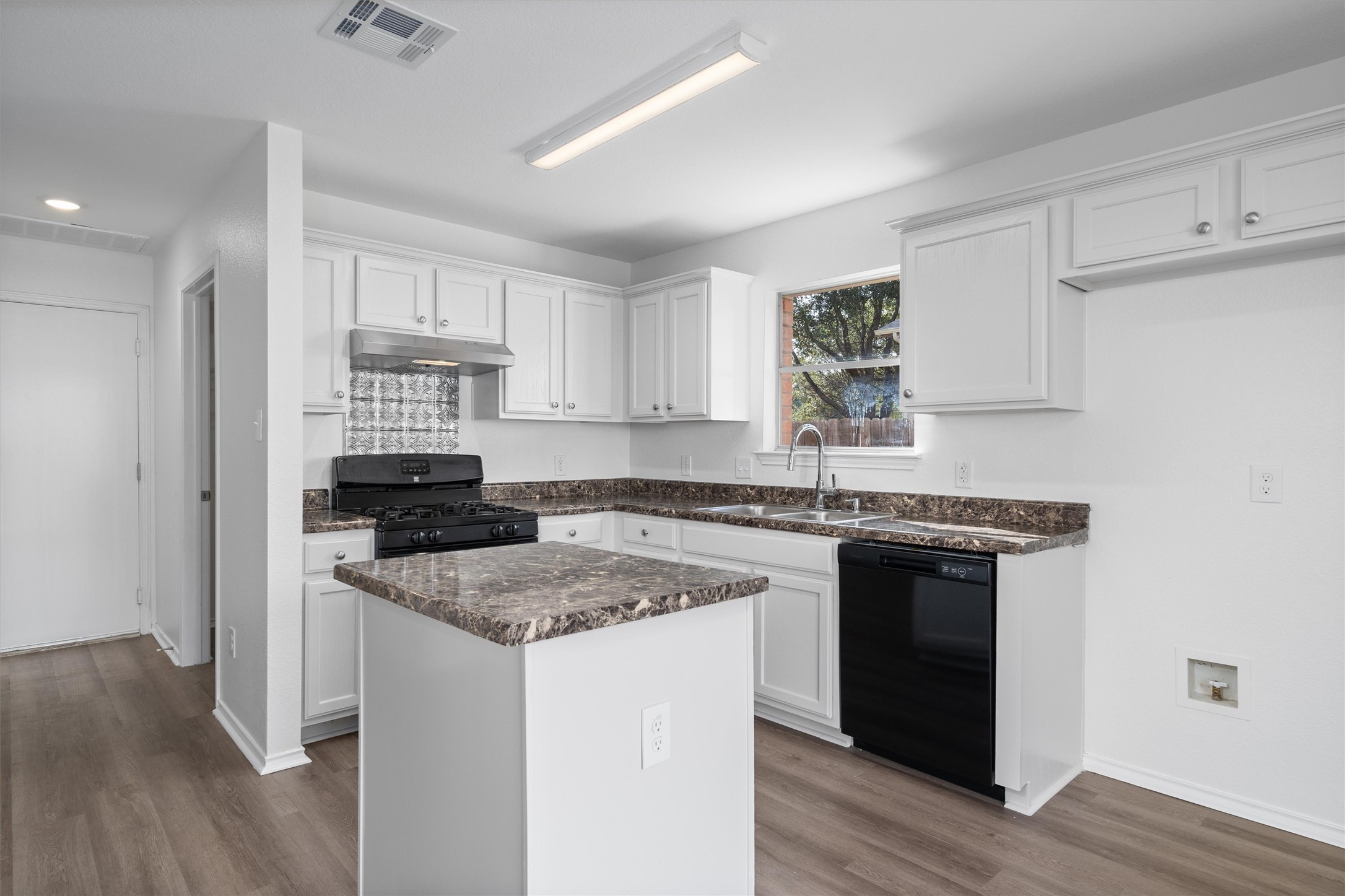 2101 Jester Farms Road Round Rock, TX 78664 - Photo 9 of 24 Kitchen featuring black appliances, white cabinets, under cabinet range hood, dark stone countertops, and dark wood finished floors