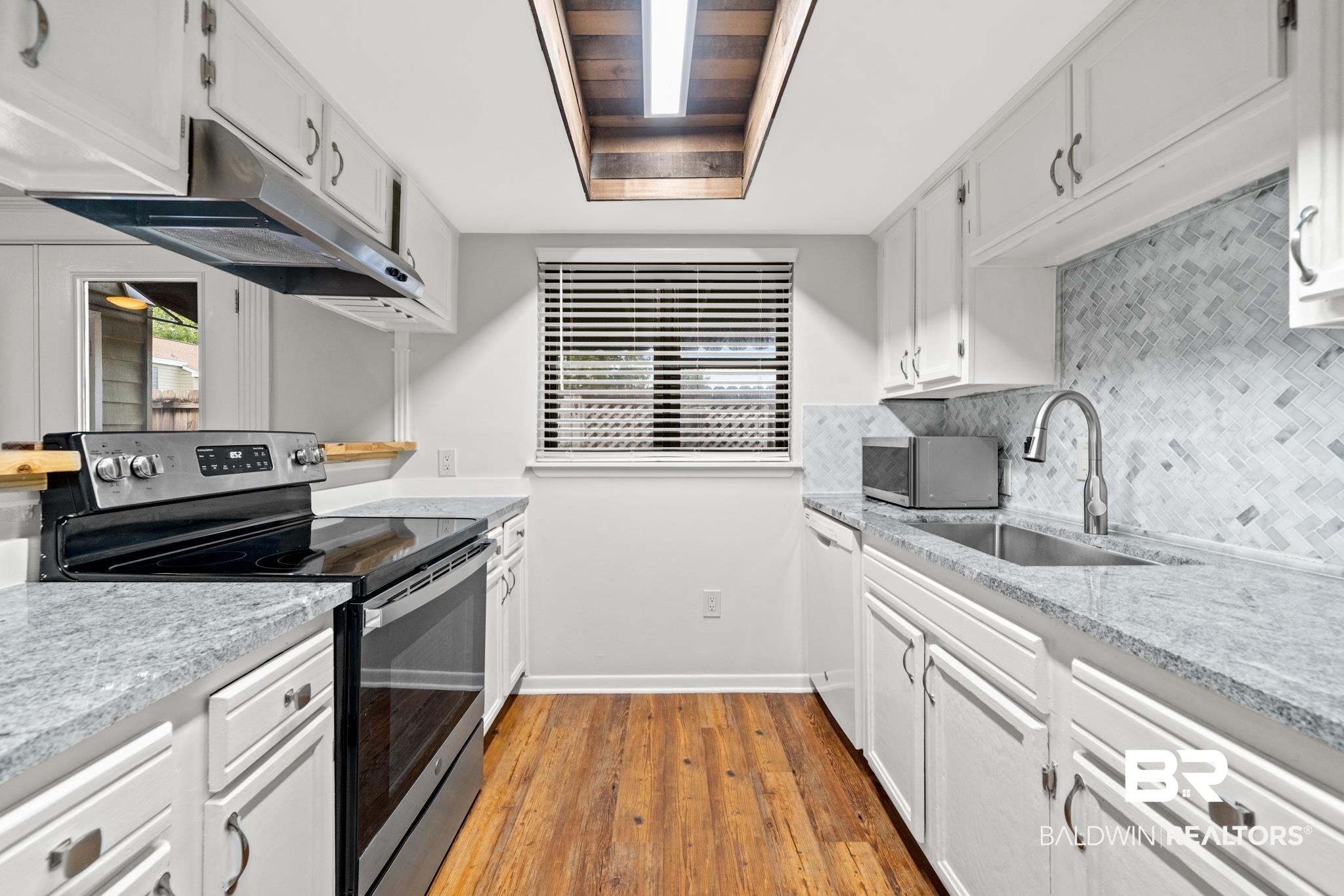 2901 Grant Street, Unit 802 Mobile, AL 36606 - Photo 13 of 37 Kitchen featuring white cabinetry, a tray ceiling, hardwood / wood-style flooring, and stainless steel range with electric cooktop