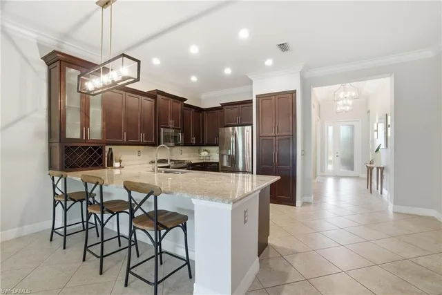 a kitchen with stainless steel appliances kitchen island granite countertop a refrigerator a stove a microwave oven a sink with a dining table and chairs