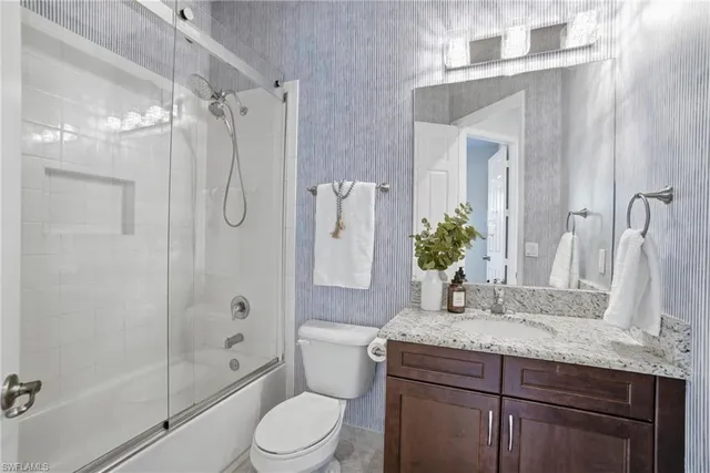 a bathroom with a granite countertop shower sink vanity mirror and toilet