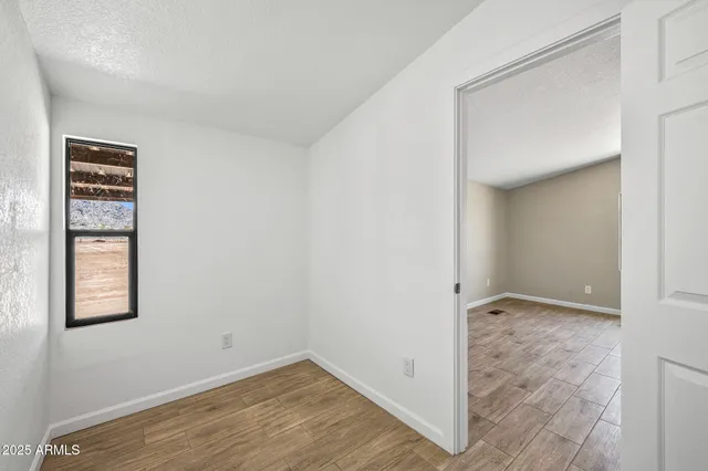 an empty room with wooden floor closet and windows