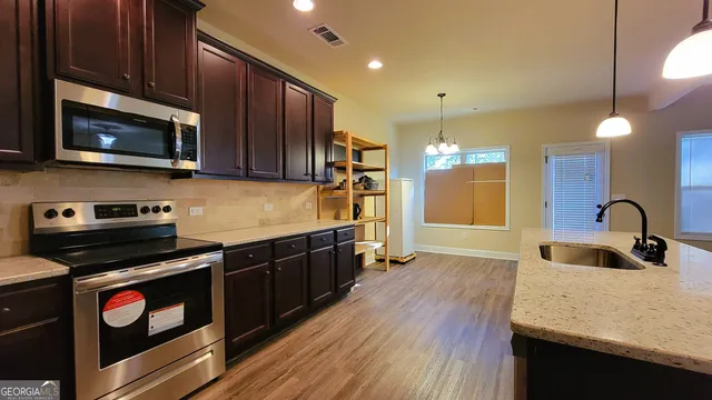 a kitchen with stainless steel appliances granite countertop wooden cabinets a sink dishwasher a stove and a refrigerator