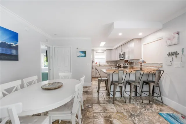 a kitchen with granite countertop kitchen island a stove a sink a refrigerator dining table and chairs