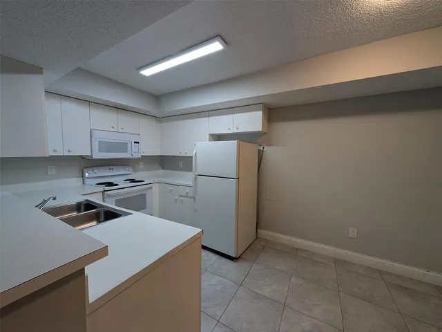 a kitchen with a refrigerator sink and cabinets