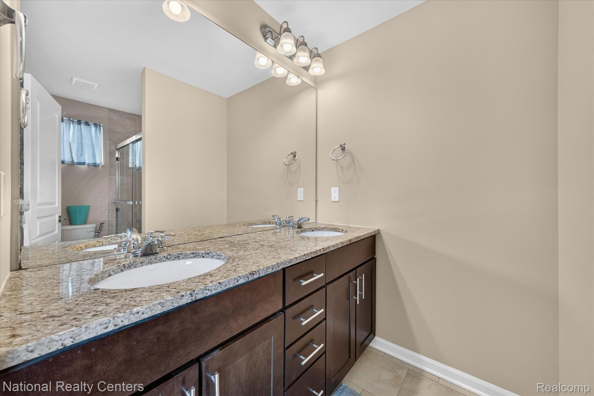 330 Glenhurst Boulevard Rochester, MI 48307 - Photo 34 of 47 Dual vanity with integrated sinks, polished chrome fixtures, expansive mirror, dark wood-finish cabinetry, and stone-finish countertop
