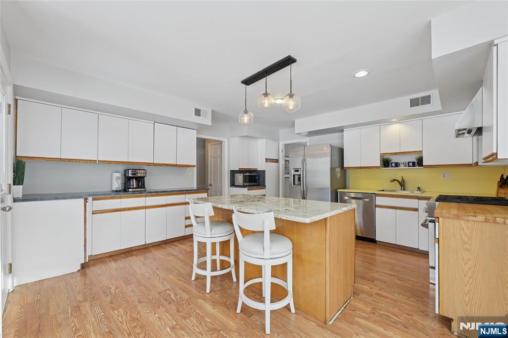 320 Park Street Haworth, NJ 07641 - Photo 21 of 48 a kitchen with a dining table chairs microwave and cabinets