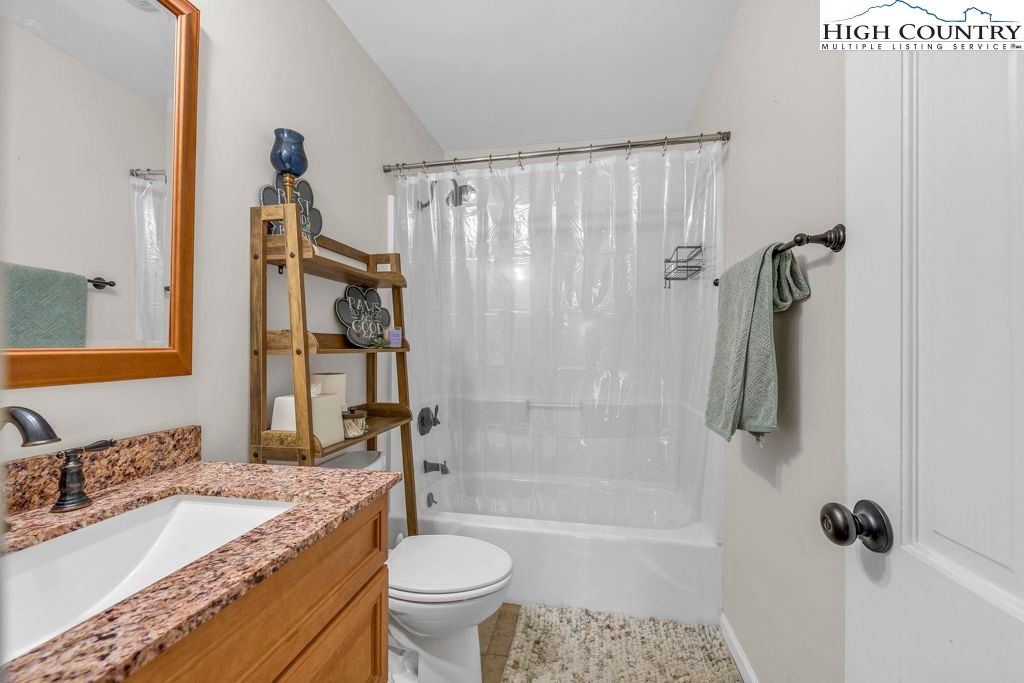 837 Pine Ridge Road Beech Mountain, NC 28604 - Photo 8 of 23 a bathroom with a granite countertop sink a toilet a mirror a bathtub and shower