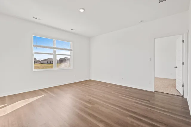 an empty room with wooden floor and window