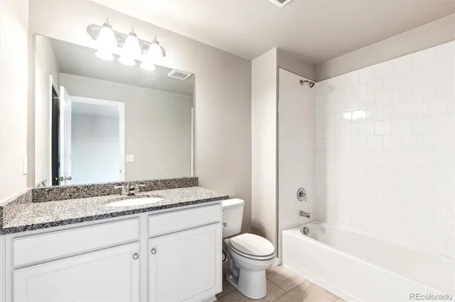 a bathroom with a granite countertop sink mirror vanity and toilet